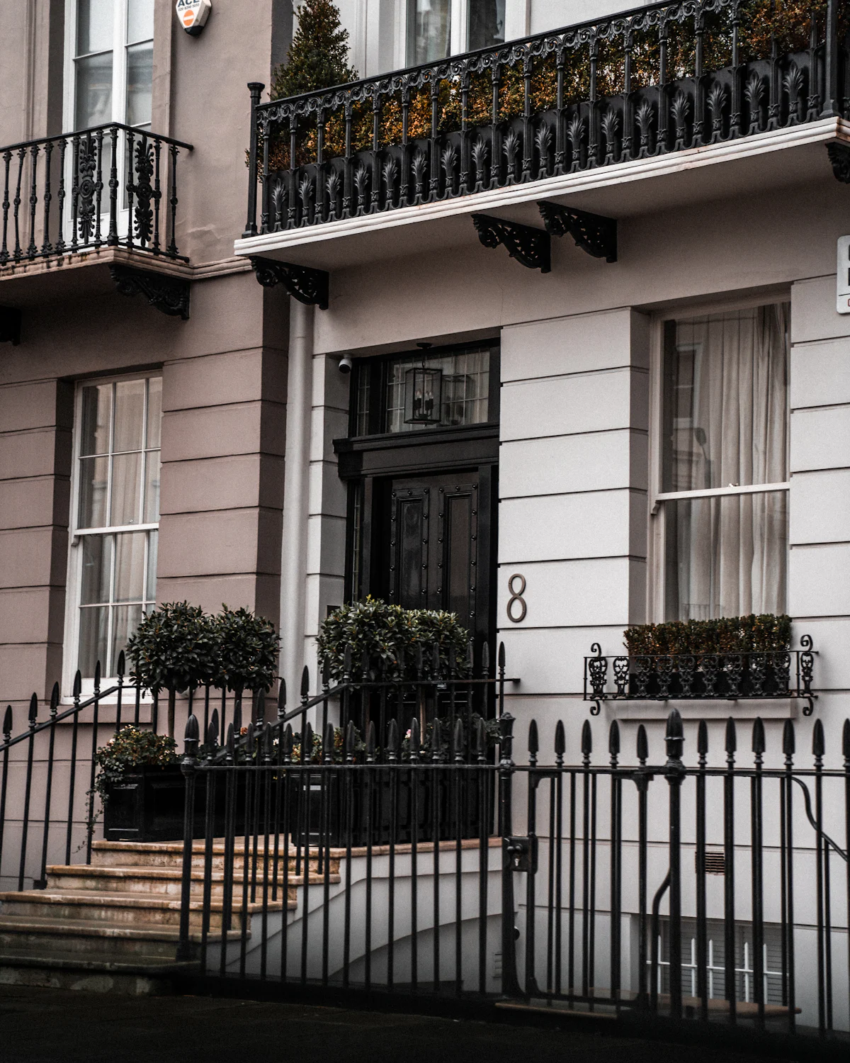 Iron railings and a black front door on a stucco London townhouse