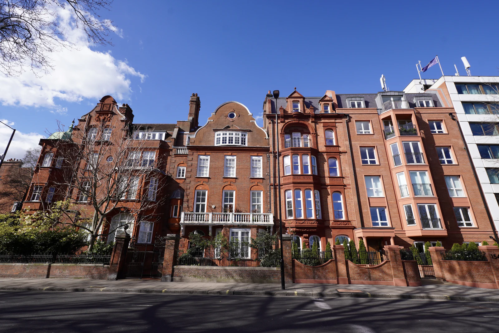 A red-brick London mansion terrace under a clear sky